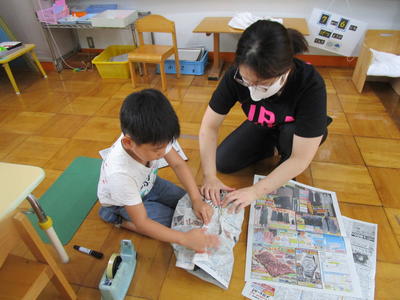 新聞紙を丸めて、てるてる坊主の顔を作っている