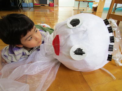 新聞紙で作ったてるてる坊主を見つめている