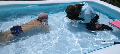 教師と子どもがビニールプールの中に入って、水に顔をつけている
