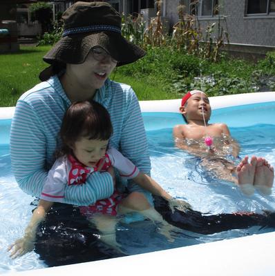 教師と子どもがビニールプールの中に入って、水に親しんでいる。