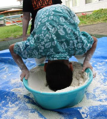 タライの中に入っている小麦粉に頭をいれて粉遊びをしている。