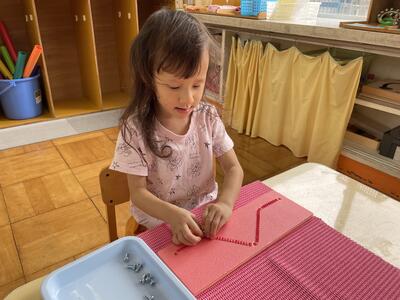 フェルトの魚の紐通し。両手を使って、5ミリの穴に紐を通します。集中！