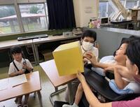 箱の中身を触って当てるゲームをしている様子です。